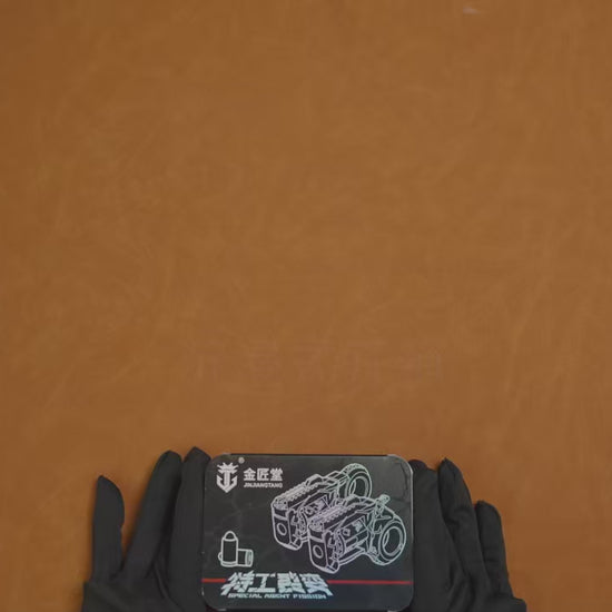 Mechanical EDC fidget revolver with rotating cylinder and ring grip, metallic silver finish, displayed on dark stone surface with modular accessories and precision details