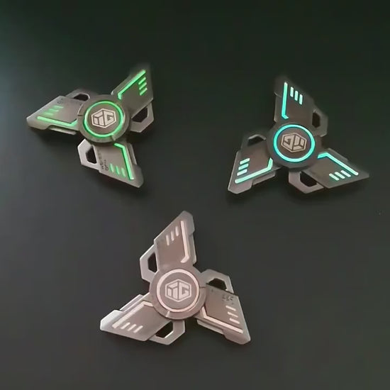 metal fidget object featuring a geometric three-blade structure with a luminous center element, designed for smooth rotational movement, tactile interaction, and visual calm with a futuristic industrial aesthetic.